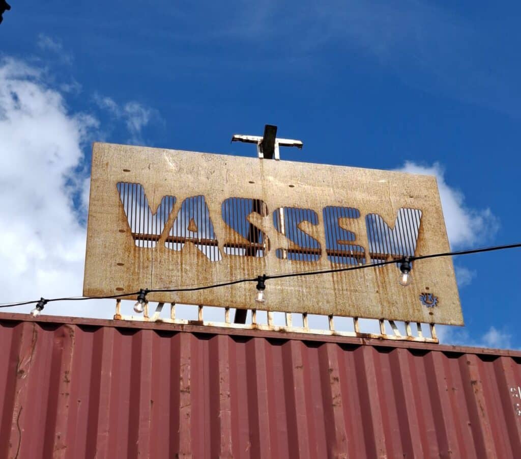 Närbild på den urskurna texten VASSEN i det vittrade stålet mot blå himmel.